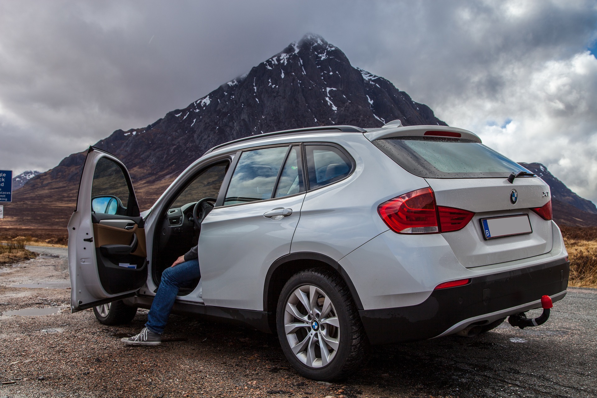 Das Auto steht vor der Bergspitze auf dem Parkplatz.