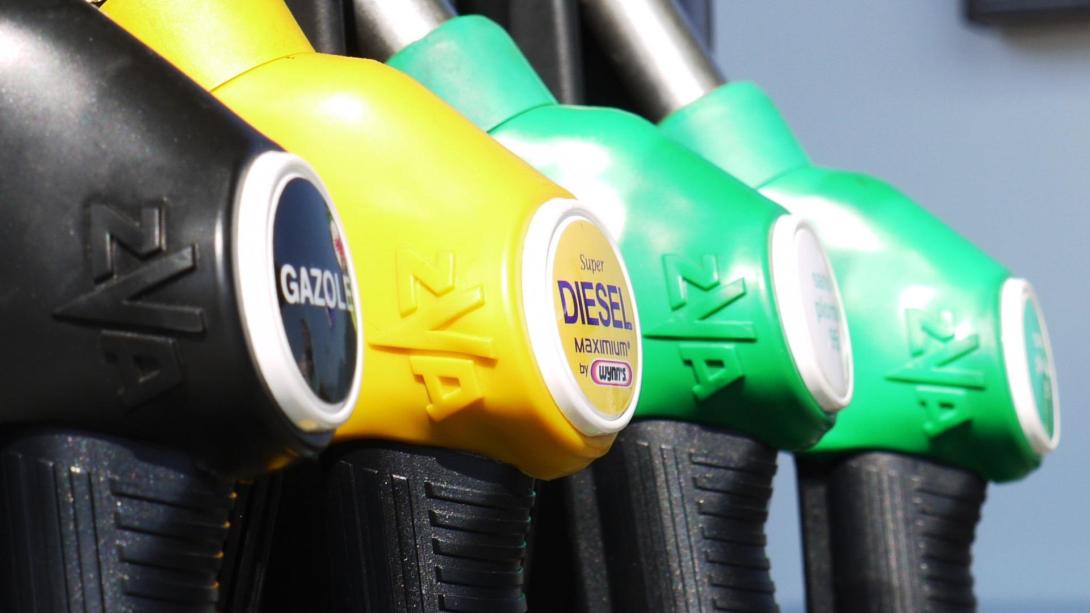  Ein Fahrzeug an einer Tankstelle, das mit Diesel betankt wird. Die Pumpe, ausgestattet mit einer grünen Düse, liefert den Treibstoff in den Tank des Automobils. Im Hintergrund sind weitere Pumpen und eine Gasflasche sichtbar, Symbole für die Energie- und Petroleumindustrie.